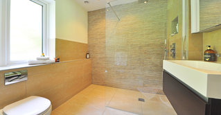 Ein Bad, welches mit braunen Natursteinplatten gefliest wurde